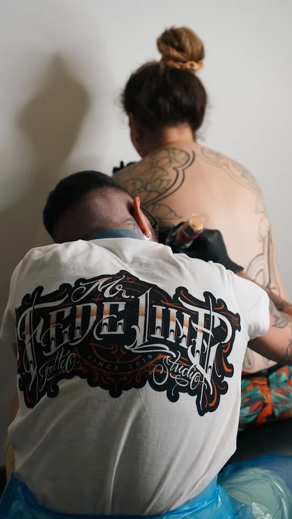 Fede al lavoro nello studio, mentre tatua la schiena di una cliente