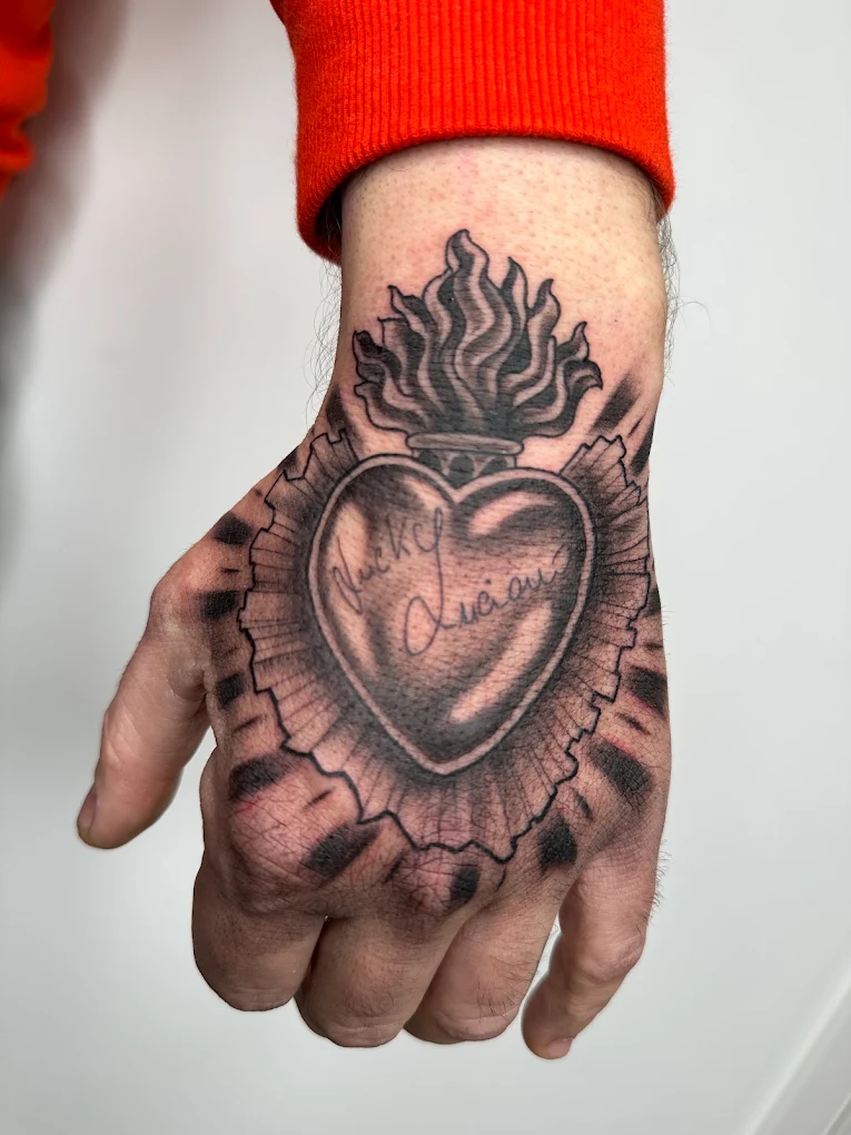 Sacro cuore fiammante tatuato sulla mano