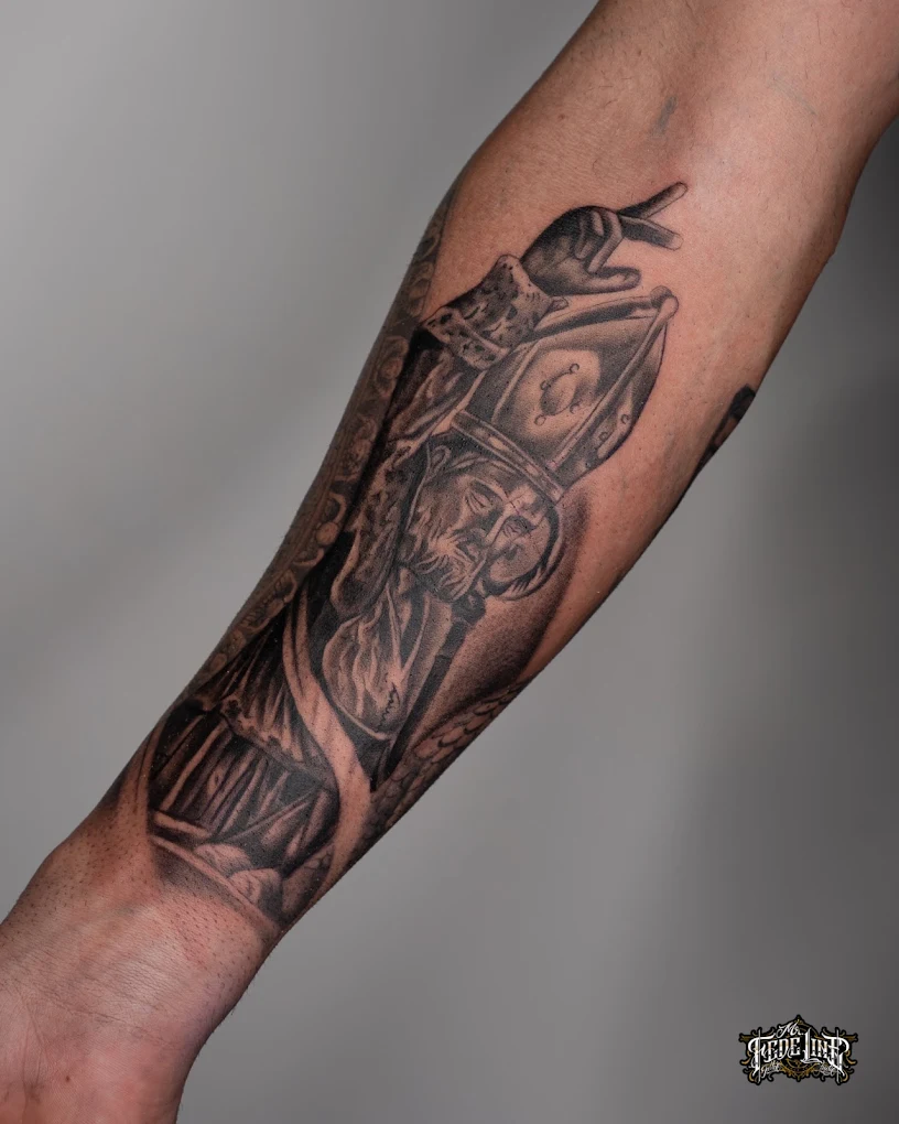 Santo con mitra e pastorale tatuato in black & grey sull'avambraccio