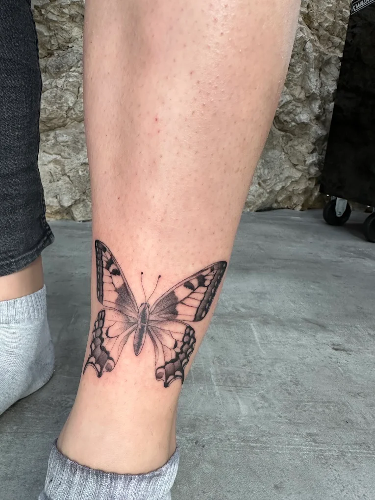 Farfalla dettagliata in fine line e puntinato tatuata sul polpaccio